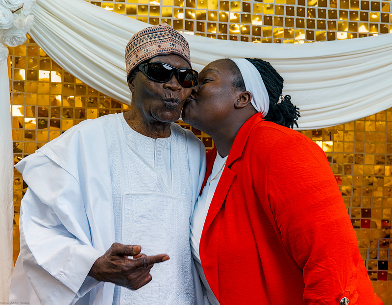A guest in a red jacket kisses the celebrant on the cheek